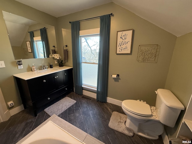 bathroom featuring vanity, wood finished floors, baseboards, lofted ceiling, and toilet