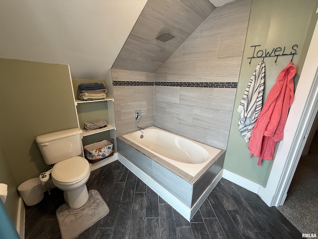 bathroom featuring toilet, a tub, a shower, baseboards, and vaulted ceiling