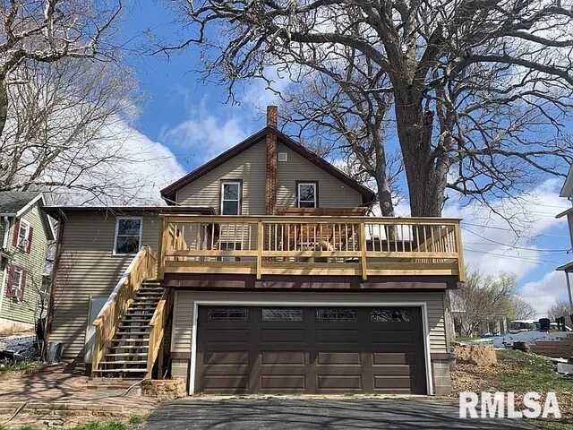 view of front facade with a deck, an attached garage, stairs, and driveway