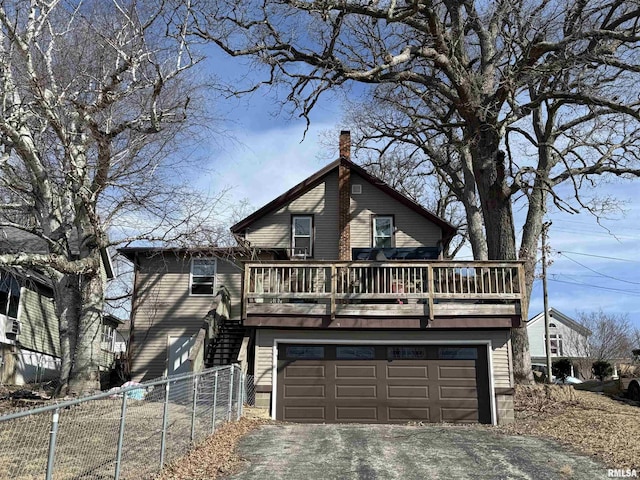 chalet / cabin with a deck, driveway, fence, stairway, and an attached garage