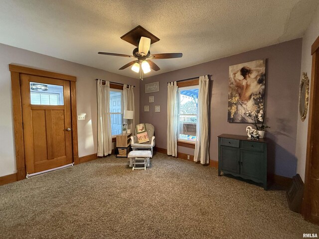 sitting room featuring baseboards, carpet, a ceiling fan, and a textured ceiling