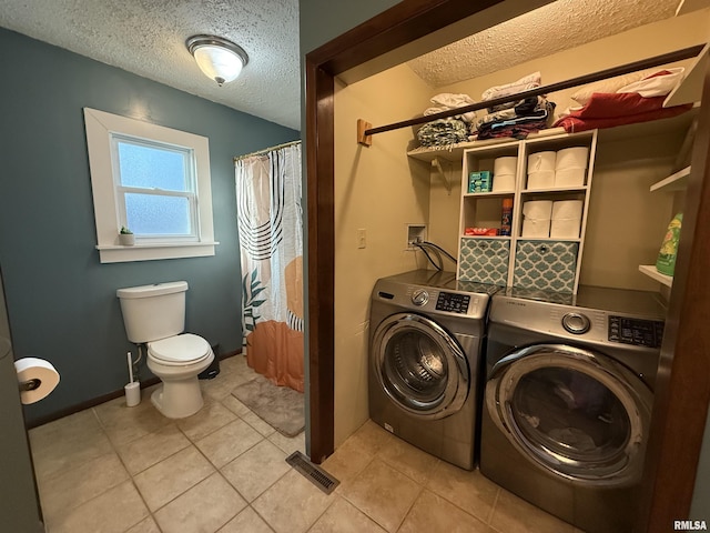 laundry room featuring a textured ceiling, laundry area, light tile patterned flooring, and washing machine and clothes dryer