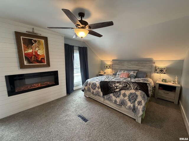 bedroom with visible vents, a large fireplace, carpet, and vaulted ceiling