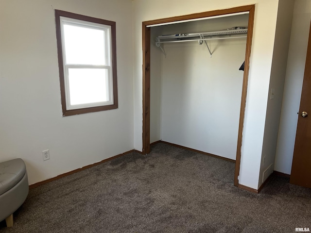 unfurnished bedroom with a closet, baseboards, and dark colored carpet