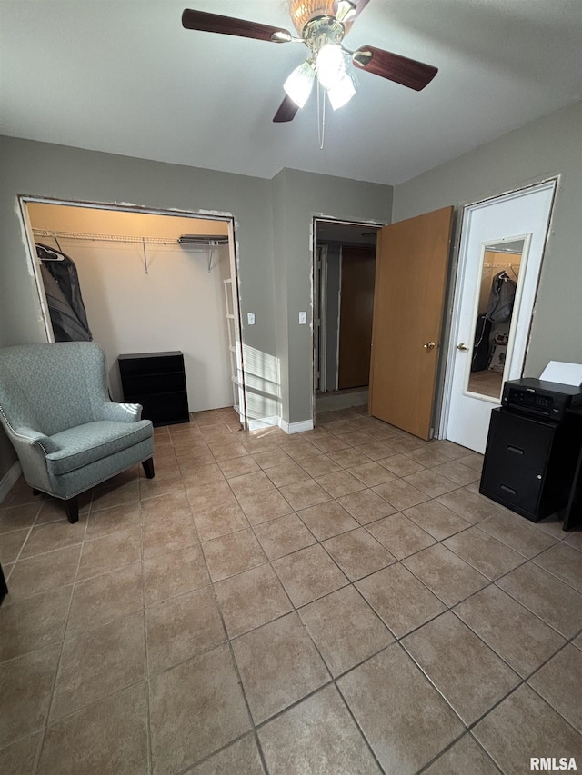 interior space featuring light tile patterned floors, baseboards, and ceiling fan