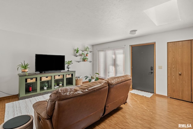 living room with light wood-style flooring, a skylight, and a textured ceiling