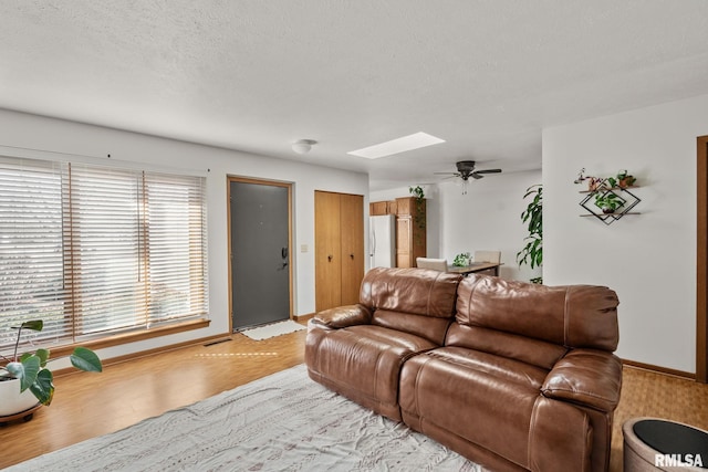 living room with visible vents, baseboards, a skylight, wood finished floors, and a textured ceiling