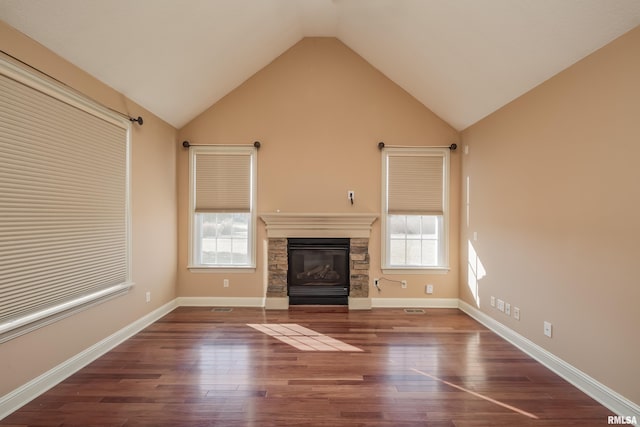 unfurnished living room featuring a stone fireplace, vaulted ceiling, wood finished floors, and baseboards