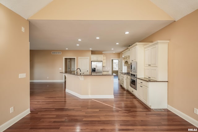 kitchen with visible vents, a sink, dark wood-type flooring, appliances with stainless steel finishes, and a kitchen island with sink