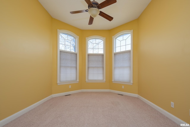 empty room featuring baseboards, light carpet, visible vents, and ceiling fan