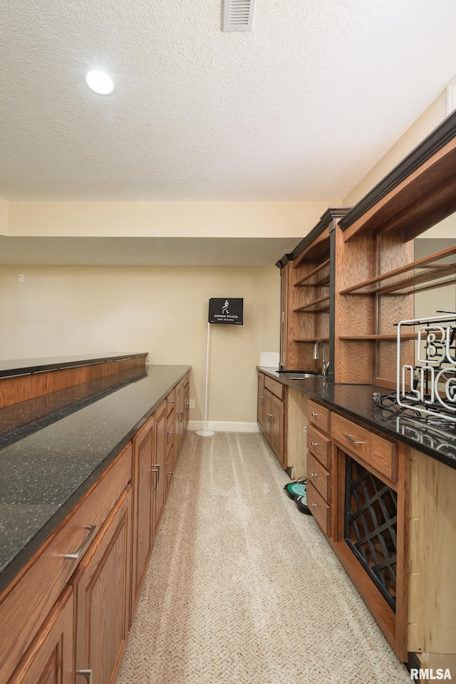 bar featuring visible vents, baseboards, light colored carpet, and a textured ceiling