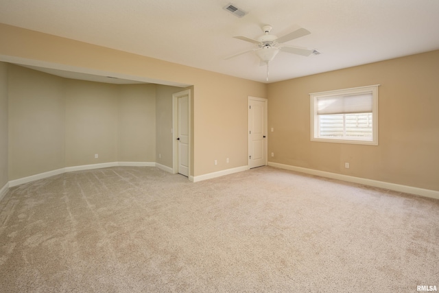 empty room featuring light carpet, visible vents, a ceiling fan, and baseboards