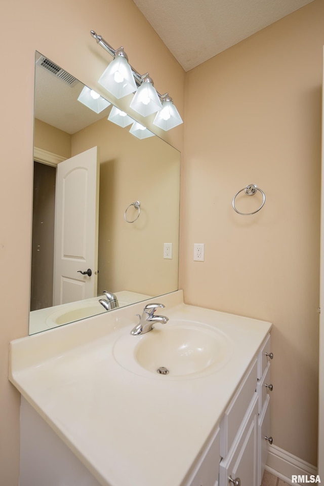 bathroom featuring visible vents, baseboards, and vanity