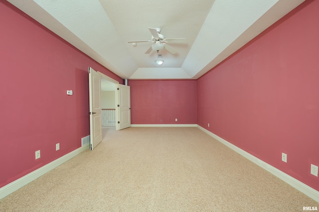 empty room featuring visible vents, light carpet, lofted ceiling, a ceiling fan, and baseboards