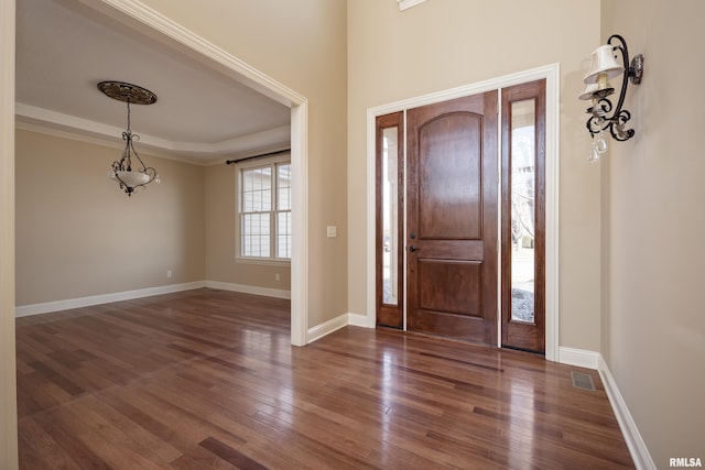 entrance foyer featuring dark wood finished floors, a tray ceiling, baseboards, and visible vents