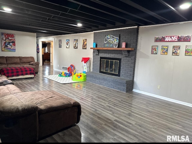 living area with a fireplace, visible vents, wood finished floors, and baseboards