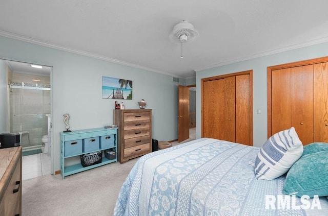 bedroom with visible vents, two closets, crown molding, light carpet, and ensuite bathroom