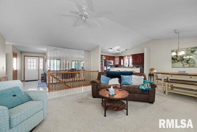 living room featuring light tile patterned floors, lofted ceiling, light colored carpet, and ceiling fan with notable chandelier