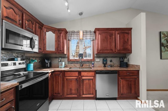 kitchen featuring light stone countertops, lofted ceiling, a sink, stainless steel appliances, and backsplash