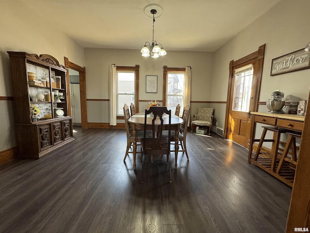 dining area with dark wood-type flooring, baseboards, and a chandelier