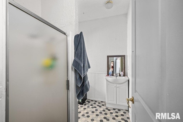 full bath with a wainscoted wall, a shower stall, and vanity