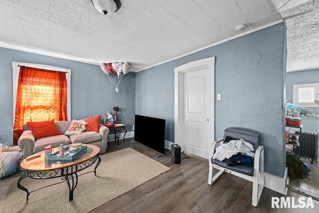 living room with crown molding, wood finished floors, baseboards, and a textured wall