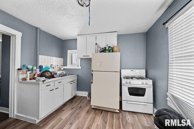 kitchen featuring white appliances, a textured ceiling, wood finished floors, and white cabinetry