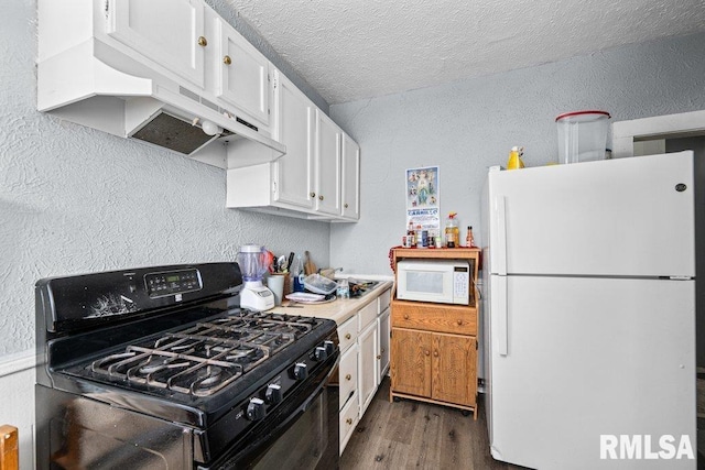 kitchen with a textured wall, wood finished floors, custom exhaust hood, white appliances, and white cabinetry