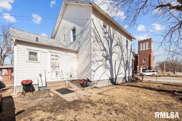 back of property with entry steps and roof with shingles