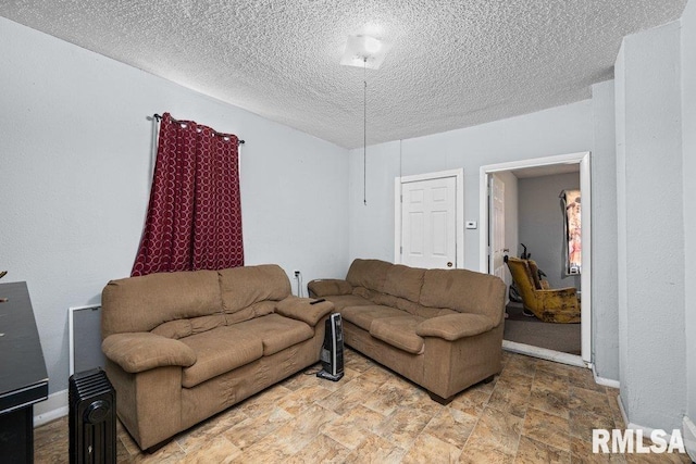 living area featuring a textured ceiling, baseboards, and stone finish flooring