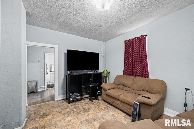 living room with stone finish floor, a textured wall, baseboards, and a textured ceiling