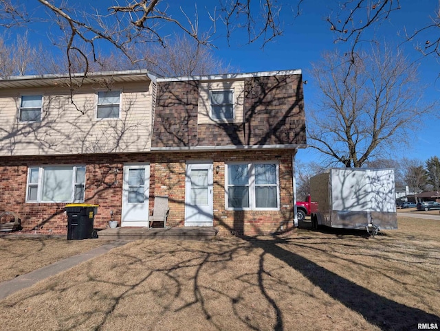 view of front of house with a front lawn, brick siding, and a shingled roof