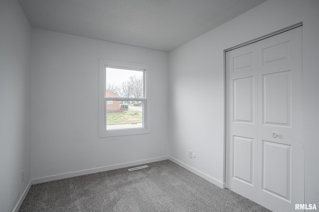 carpeted spare room with baseboards and visible vents