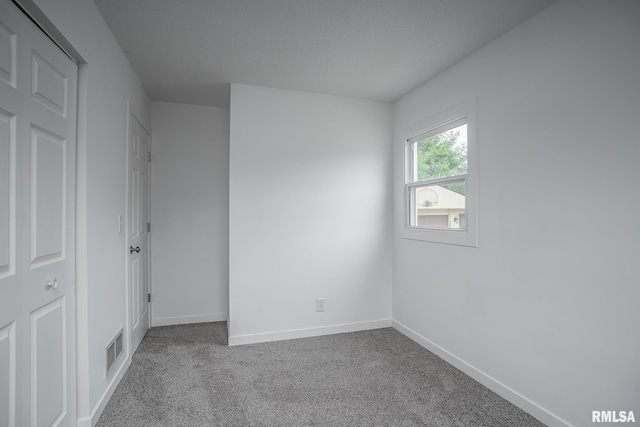 carpeted empty room featuring baseboards and visible vents