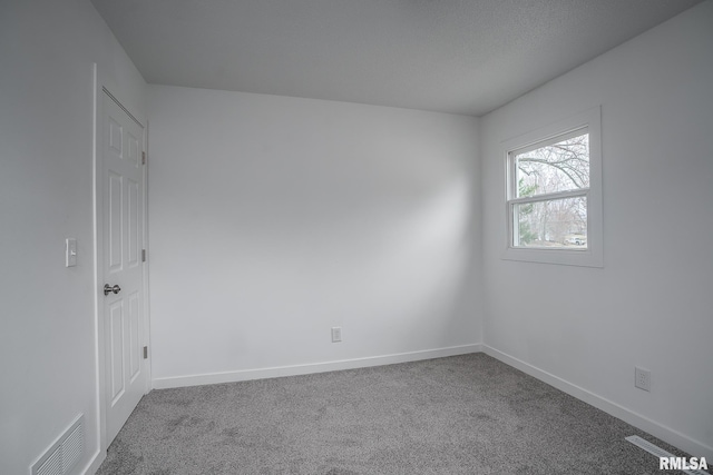 carpeted empty room featuring visible vents and baseboards