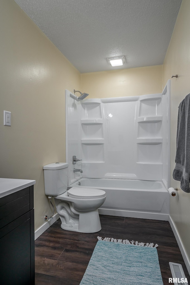 full bathroom with wood finished floors, a textured ceiling, toilet, and shower / washtub combination