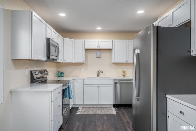 kitchen with recessed lighting, dark wood-style floors, stainless steel appliances, a sink, and white cabinetry