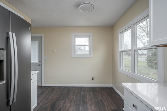 unfurnished dining area with dark wood finished floors, baseboards, and a healthy amount of sunlight
