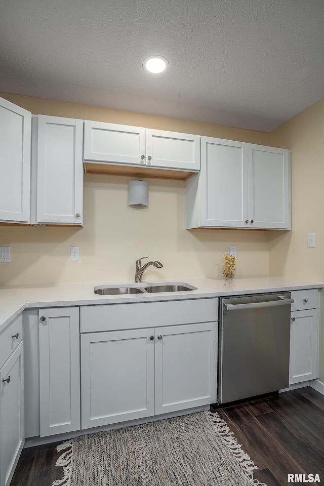 kitchen with white cabinets, stainless steel dishwasher, a sink, and dark wood-style floors