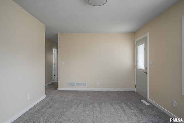 empty room with baseboards, a textured ceiling, visible vents, and carpet