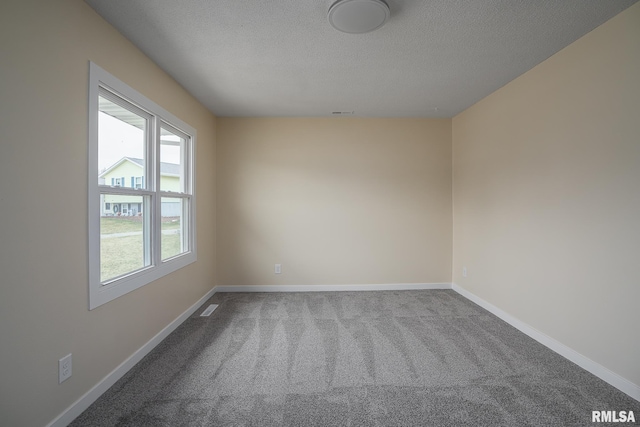 carpeted empty room featuring a textured ceiling, baseboards, and visible vents