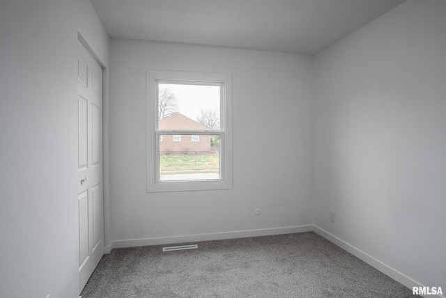 carpeted spare room featuring visible vents and baseboards
