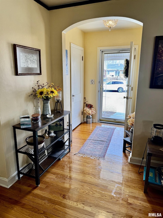 foyer entrance featuring wood finished floors, arched walkways, and baseboards