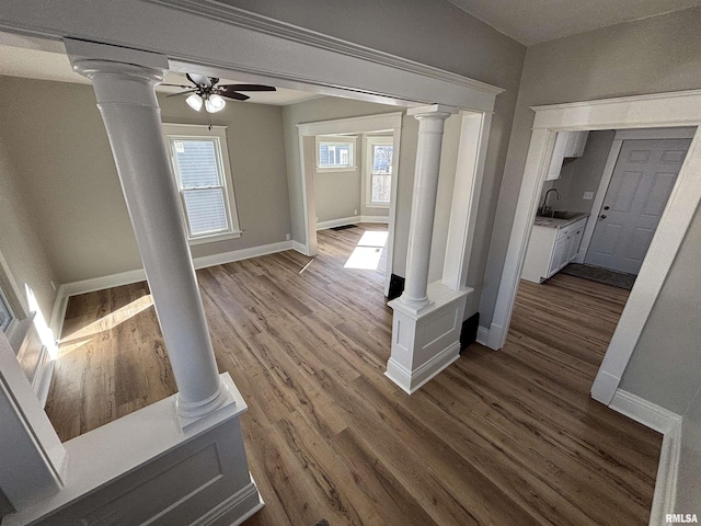 interior space featuring a sink, dark wood-style flooring, baseboards, and decorative columns