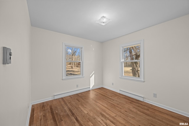 spare room with wood finished floors, baseboards, and a baseboard radiator