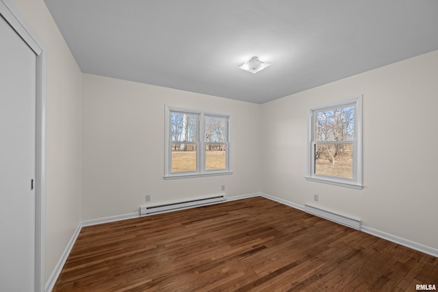 empty room with a baseboard heating unit, baseboards, dark wood-style flooring, and a baseboard radiator