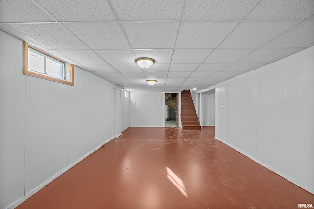 below grade area with a paneled ceiling and stairs