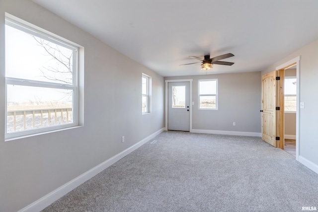 spare room featuring baseboards, light carpet, and a ceiling fan