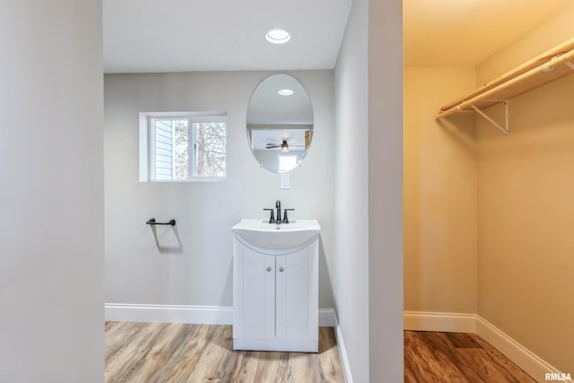 bathroom with recessed lighting, vanity, baseboards, and wood finished floors