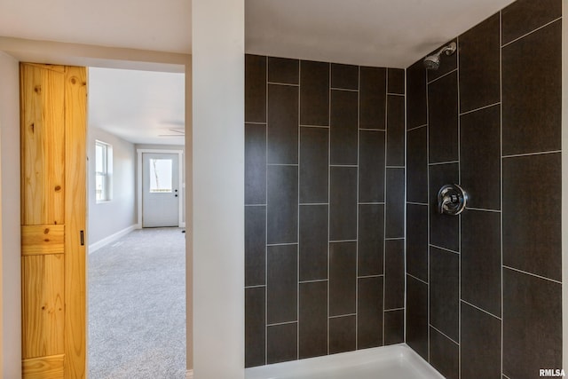 full bath featuring baseboards and a tile shower